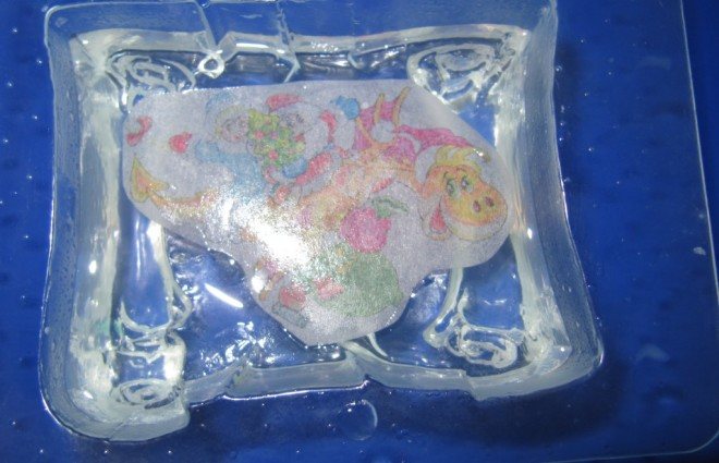 Дожидаемся, когда мыло чуть остынет, но не потеряет жидкой консистенции. Сбрызгиваем его спиртом из пульверизатора и кладем сверху карточку – пригласительный, слегка утапливая