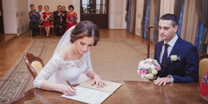 Молодые расписываются в регистрационной книге