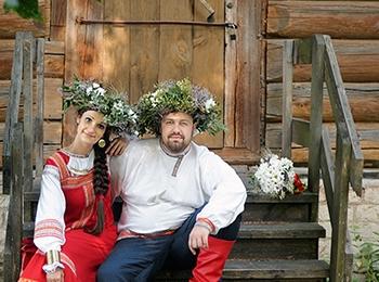 Молодые в зеленых венках и свадебных нарядах с красными элементами