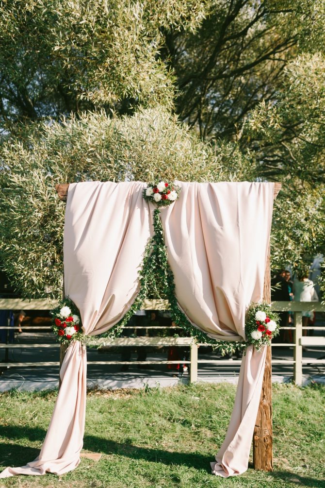 Свадебная арка украшенная цветами и тканью. Белая ткань придает арке более романтического внешнего вида.