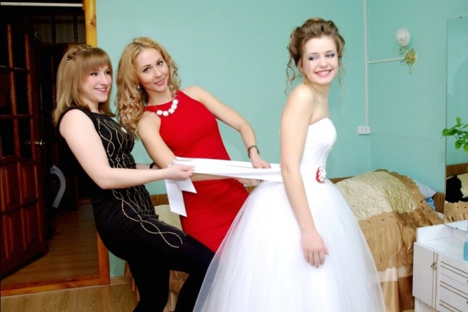 Свидетельница одевает платье невесте