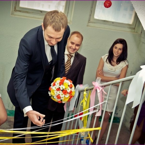 жених перерезает ленту в подъезде невесты